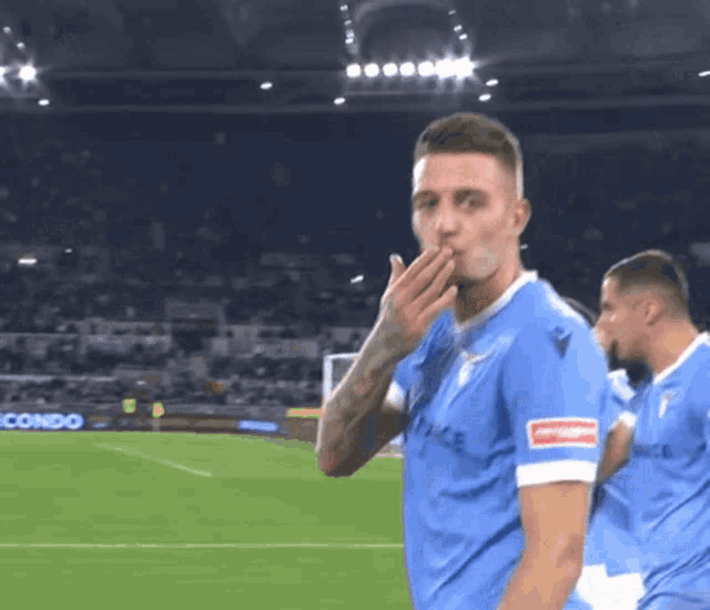 a soccer player covering his mouth with his hand on a soccer field