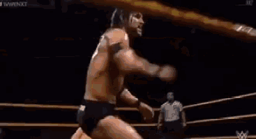 two men are wrestling in a ring and one of them is laying on the floor .