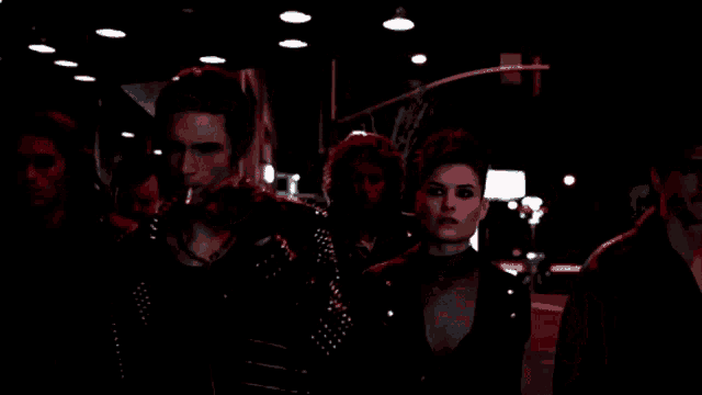 a group of people walking down a dark street at night