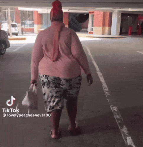 a woman in a pink shirt is walking in a parking lot with a tiktok hashtag