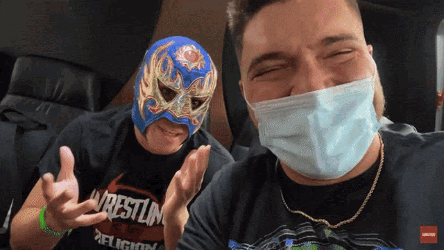 a man wearing a mask next to a man wearing a wrestling shirt
