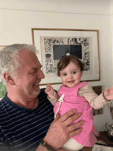 a man holding a baby in front of a framed picture that says ' a ' on it