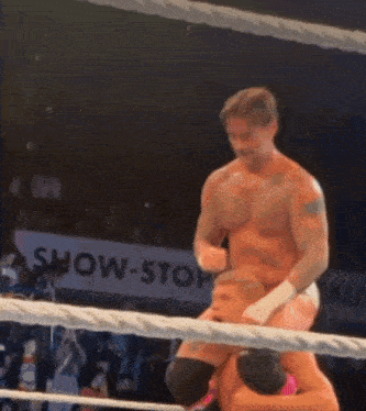 a man in a boxing ring with a sign in the background that says shocking