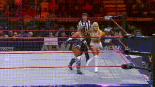 two women are wrestling in a wrestling ring with a referee watching .