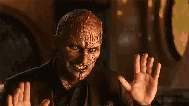 a man with a devil 's face is holding his hands up in front of his face .