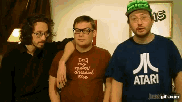 a man wearing a shirt that says my mom dressed me stands next to two other men