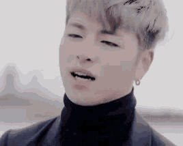a young man wearing a black turtleneck and earrings