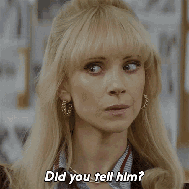 a woman with blonde hair and hoop earrings says " did you tell him "