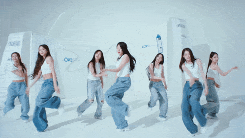 a group of women are dancing in front of a wall that has the word love on it