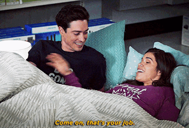 a man and a woman are laying in bed and the woman is wearing a purple shirt that says great minds