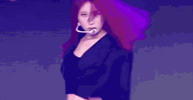 a woman with red hair is standing in front of a microphone and making a rock sign .