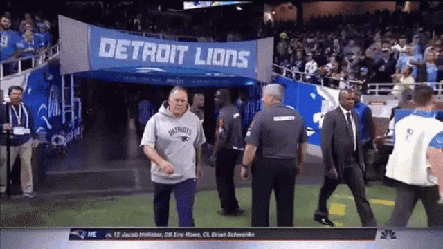 a man in a patriots sweatshirt walks into a detroit lions entrance