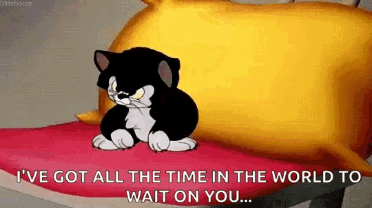 a cartoon cat is sitting on a bed with a yellow pillow and a red blanket .