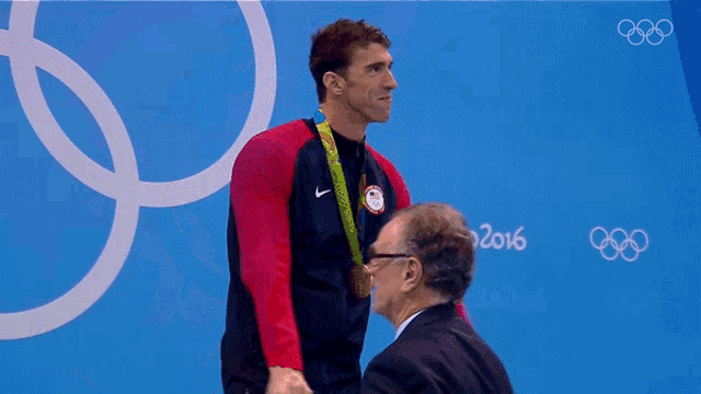 a man stands in front of a sign that says " rio 2016 "