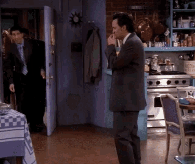 a man in a suit standing in a kitchen