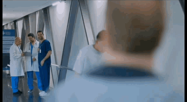 a group of doctors and nurses are standing in a hospital hallway talking to each other