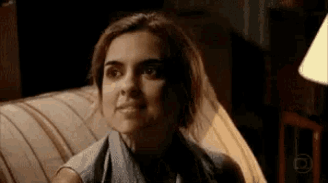 a woman is sitting on a couch with a towel around her neck and smiling .