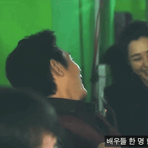 a man and a woman are laughing in front of a green screen .