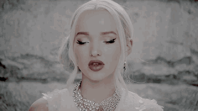 a close up of a woman wearing a white dress and necklace