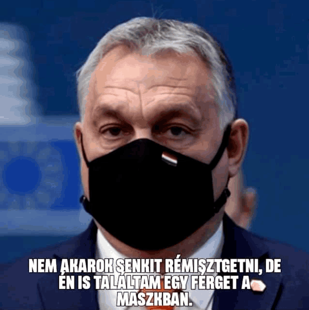 a man in a suit and tie wearing a black face mask with a foreign language caption