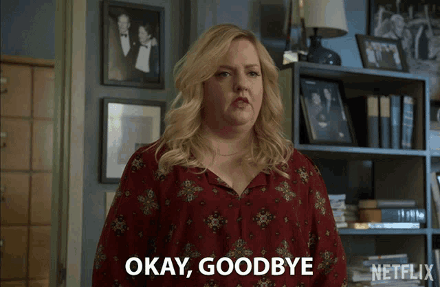a woman says " okay goodbye " in front of a shelf full of pictures