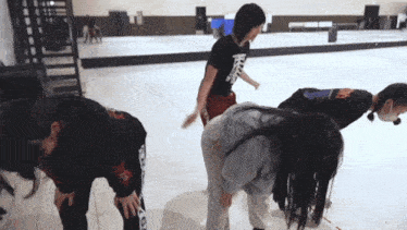 a woman wearing a black shirt with the letter t on it is bending over