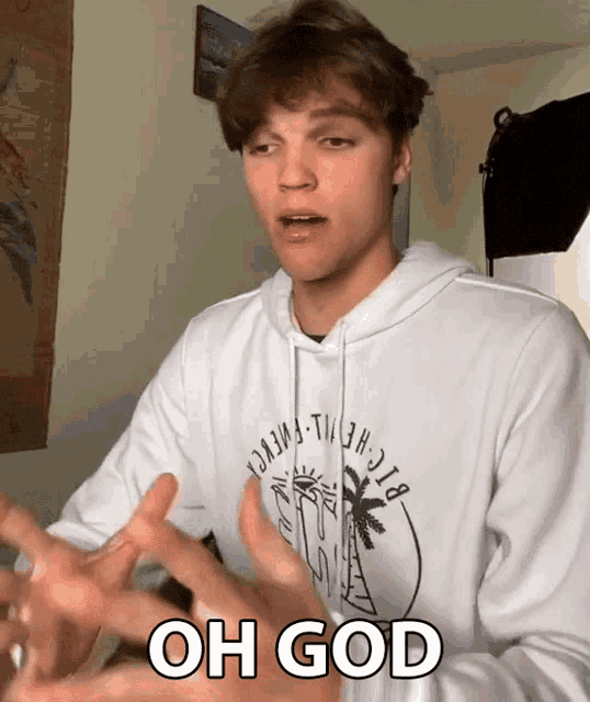a young man wearing a white hoodie with the words oh god on it