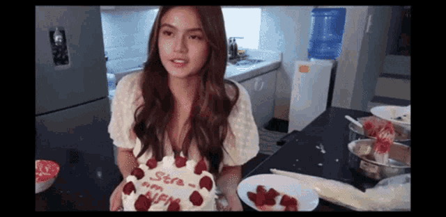 a woman in a kitchen holding a cake that says stre on it