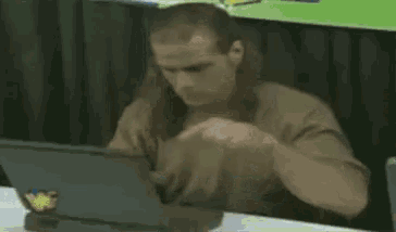a man wearing a pentakill shirt sits at a desk