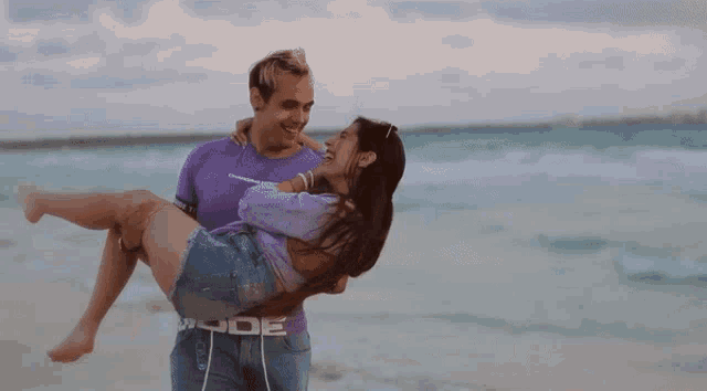 a man is carrying a woman in his arms with a purple shirt that says league on it