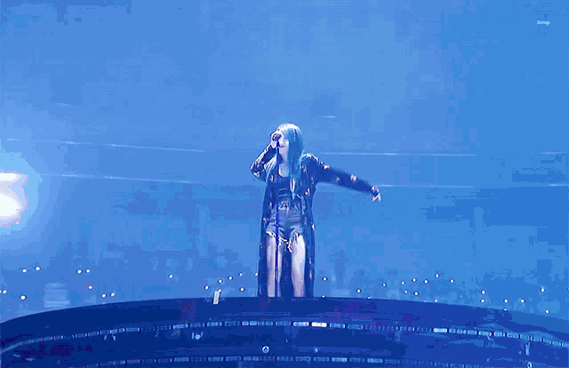 a woman with blue hair singing into a microphone
