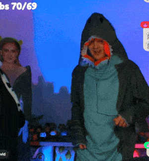 a man in a shark costume stands in front of a screen that says bs70 69