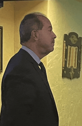 a man in a suit and tie stands in front of a wall