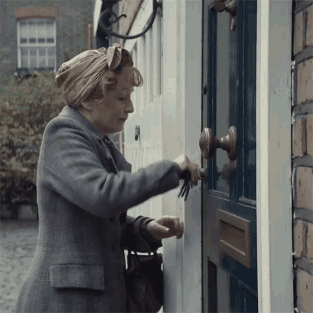 a woman knocking on a door with a mailbox underneath