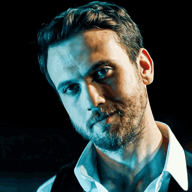 a man with a beard wearing a white shirt and black vest