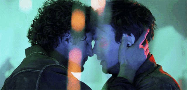 two men are touching each other 's foreheads in a blurry photo