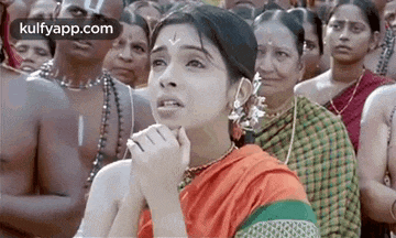 a woman is sitting in front of a crowd of people and making a funny face .