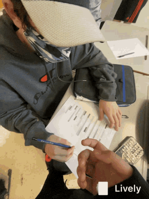 a person wearing a champion sweatshirt is sitting at a desk