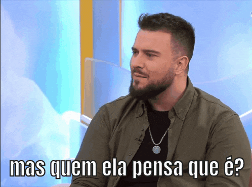 a man with a beard is sitting in front of a screen that says mas quem ela pensa que e?