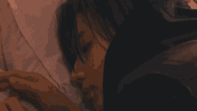 a woman is laying on a bed with her head on a pillow