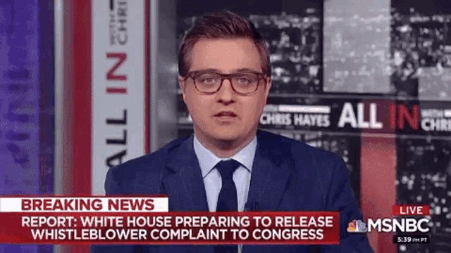 a man in a suit and tie is standing in front of a breaking news banner .