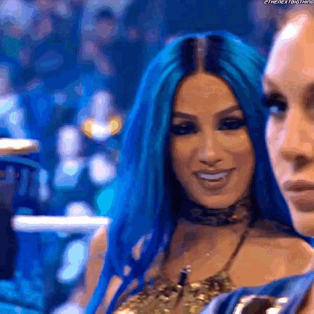 two women with blue hair are smiling for the camera .