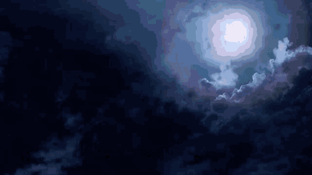 a full moon is shining through the clouds in a dark night sky .