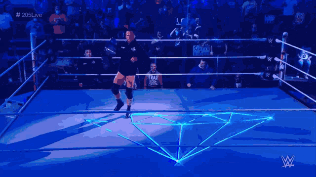 a wrestler is walking out of a wrestling ring with # 205live written on the bottom