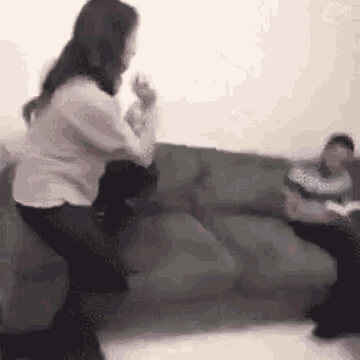 a woman is standing next to a man sitting on a couch .