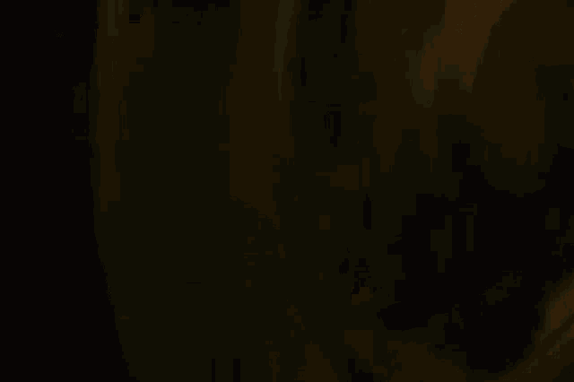 a blurred image of a person standing in a dark room with a phone in the foreground .