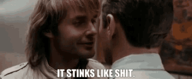 two men are touching each other 's faces and one of them says it stinks like shit