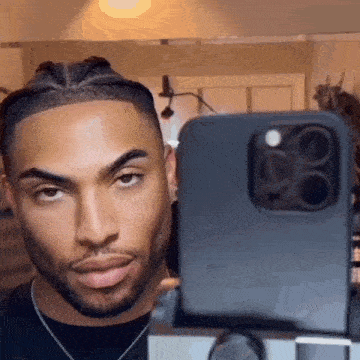 a man with a beard is taking a selfie with his cell phone .