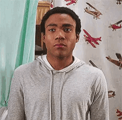 a man in a gray hoodie is standing in front of a wall with airplanes on it .