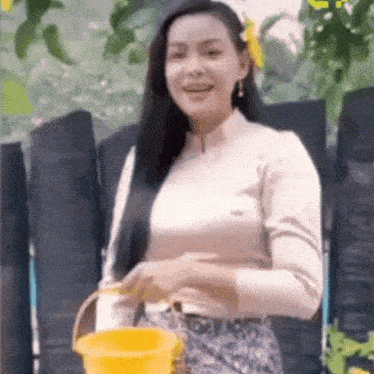 a woman is holding a yellow bucket in her hands .